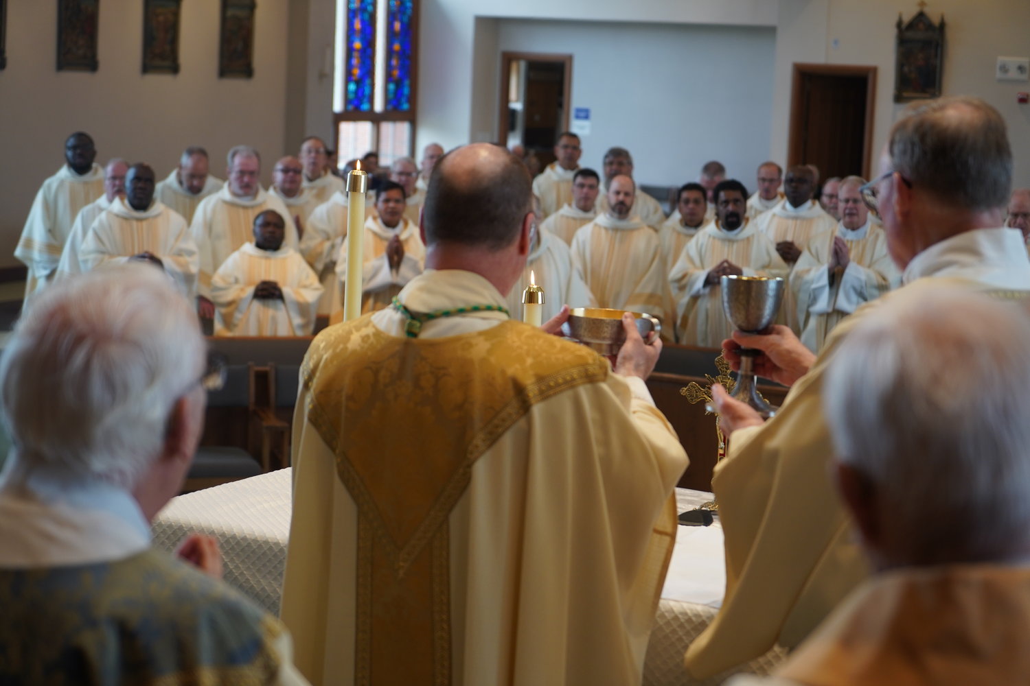 Bishop W. Shawn McKnight, assisted by Deacon John Schwartze, elevates the Most Blessed Sacrament while he and priests of the diocese pray the Doxology together during the Chrism Mass on April 12 in St. Andrew Church in Holts Summit. — Photo by Jay Nies
